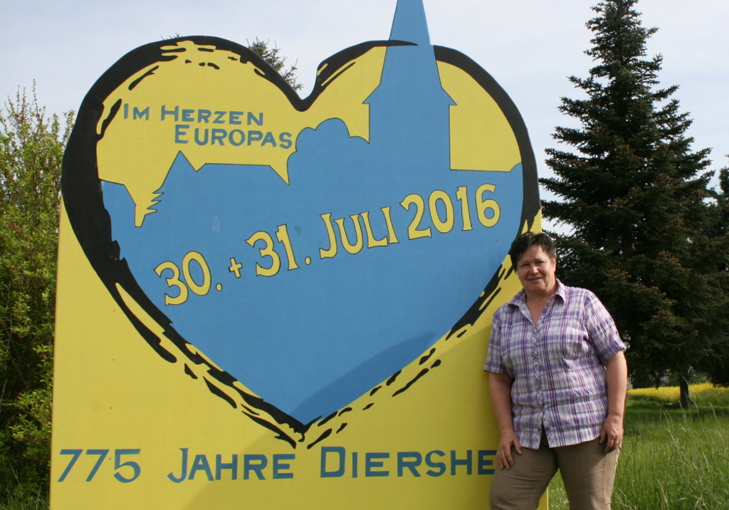 Ortsvorsteherin Doris Bleß vor einem der großen Schilder, die seit dem 1. Mai über das Dorfjubiläum informieren.