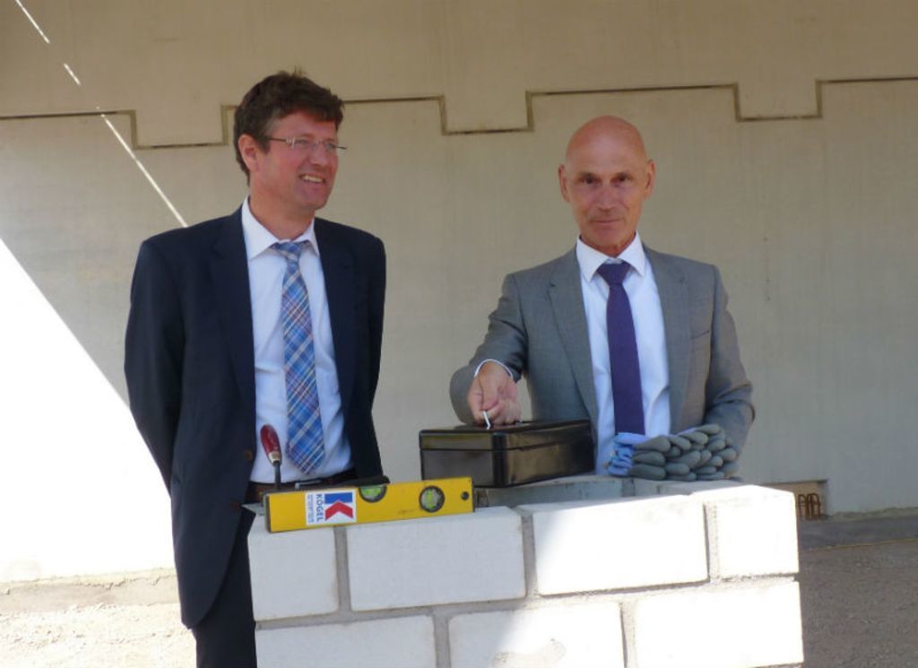 Firmeninhaber Matthias Bader und Baubürgermeister Oliver Martini mauern eine Kassette „für die Ewigkeit“ ein.
