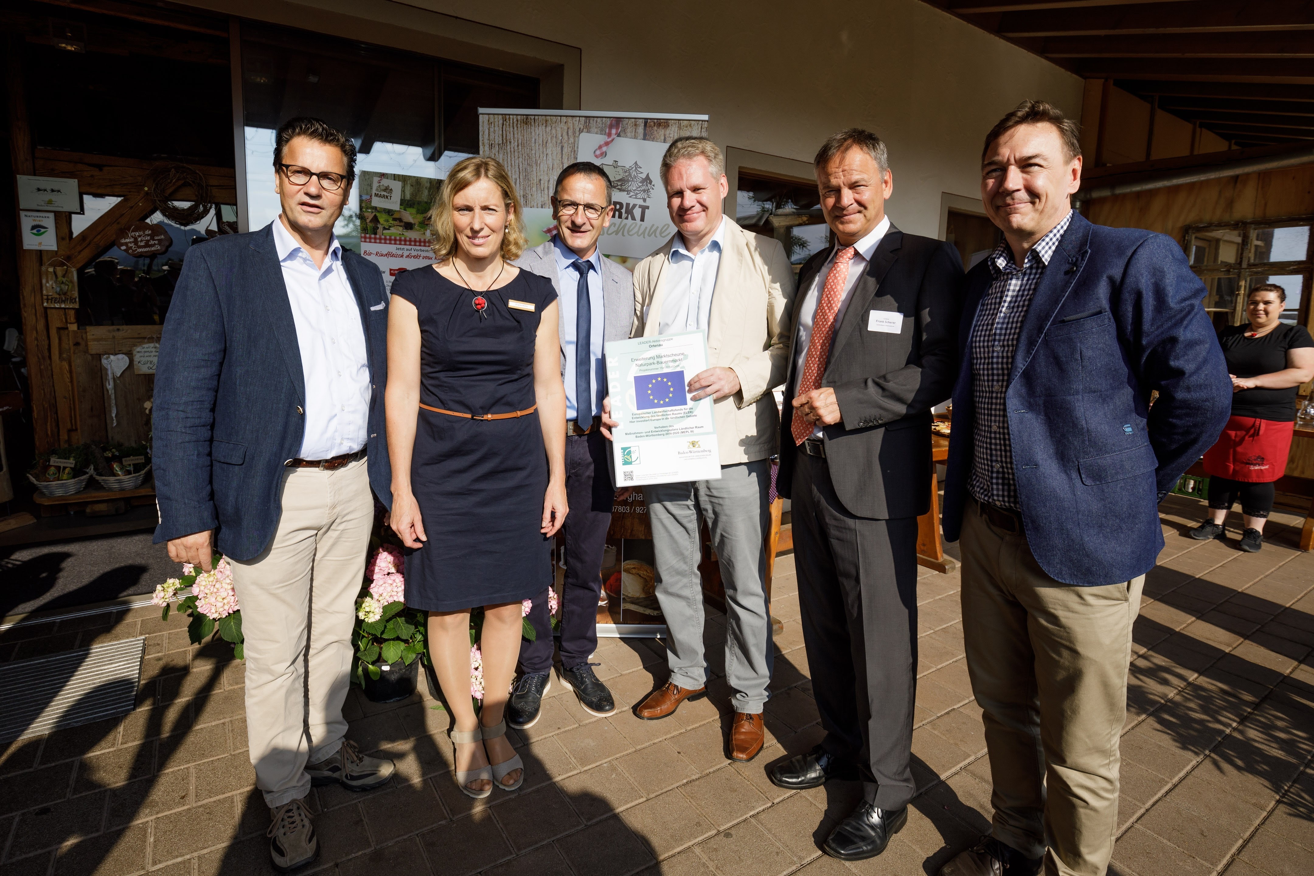 Minister Peter Hauk (v.l.), Inhaber-Ehepaar Brigitte und Ulrich Müller, Ulrich Döbereiner, Landrat Frank Scherer und Thorsten Neumann, Betriebsleiter Markt-Scheune