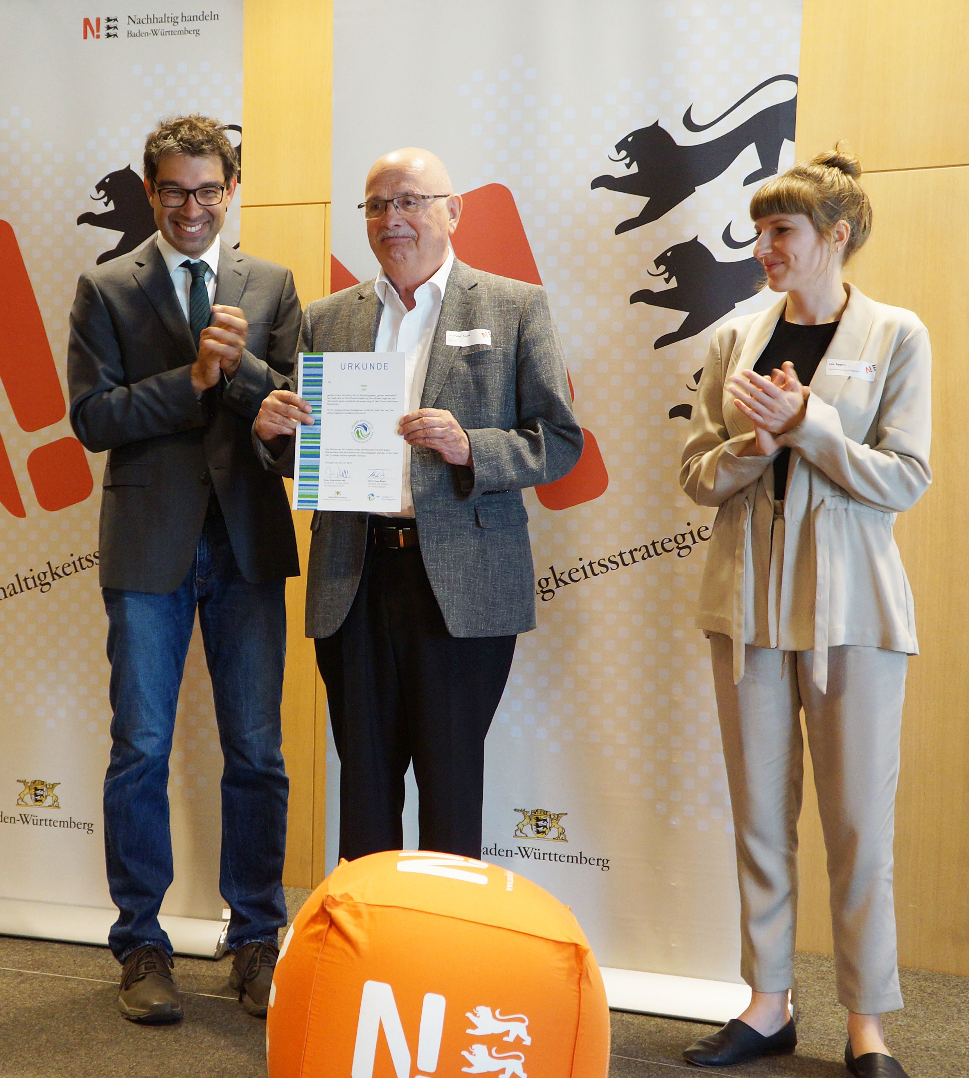 Walter Caroli (Mitte) erhält als Vertreter der Stadt Lahr von Staatssekretär André Baumann (Umweltministerium Baden-Württemberg) und Lea Eggers (Initiative Pro Recyclingpapier) die Urkunde „Recyclingpapierfreundliche Kommune“
