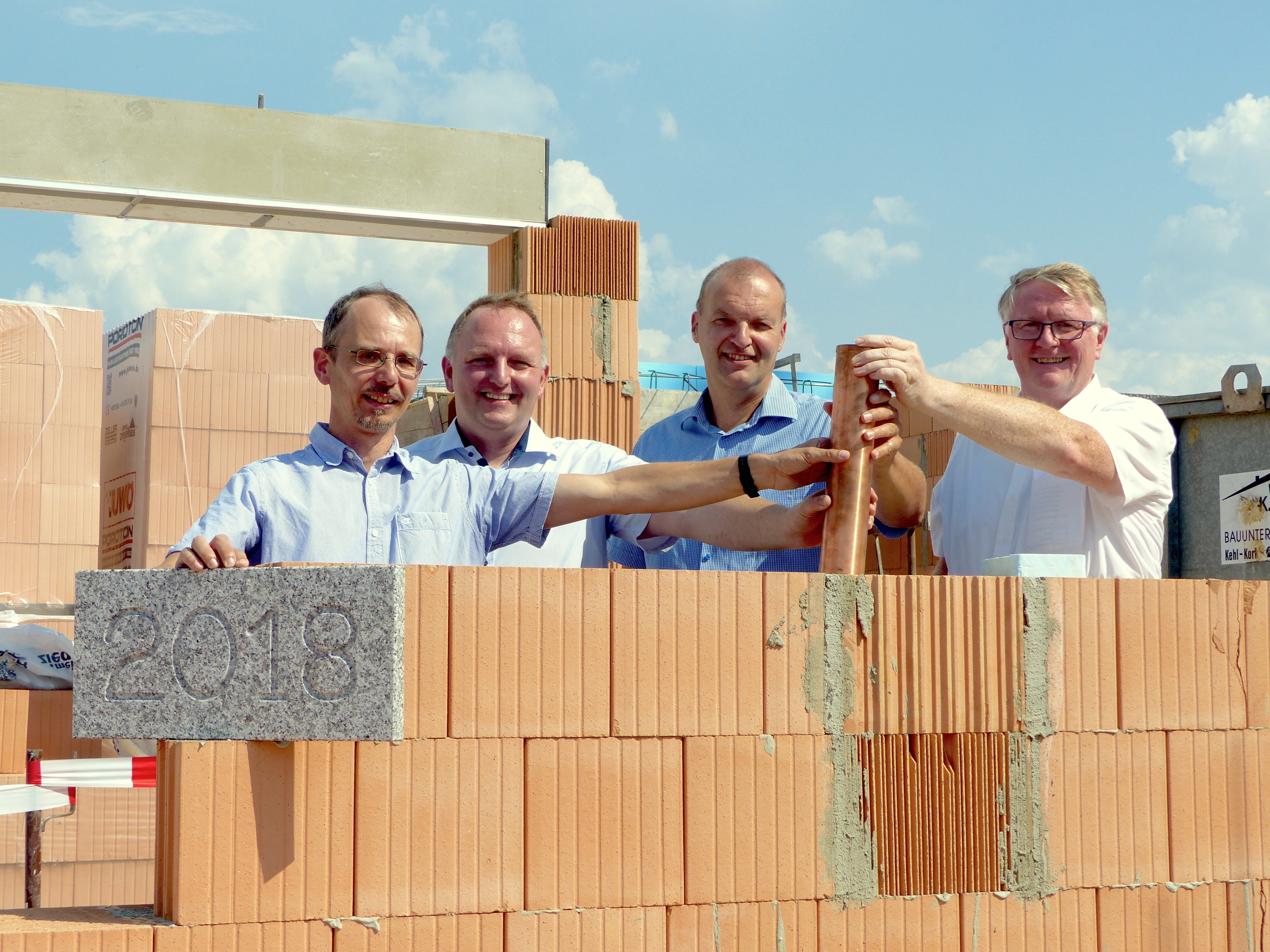 Gemeinsam versenkten Christian Ascherl, Leiter des Wohnverbunds, Architekt Rolf-Dieter Schink, Neurieds Bürgermeister Jochen Fischer und der Vorstandsvorsitzende der Diakonie Kork, Frank Stefan (v. l.), die Kapsel mit den Zeitdokumenten in den entstehenden Mauern des Gebäudes.