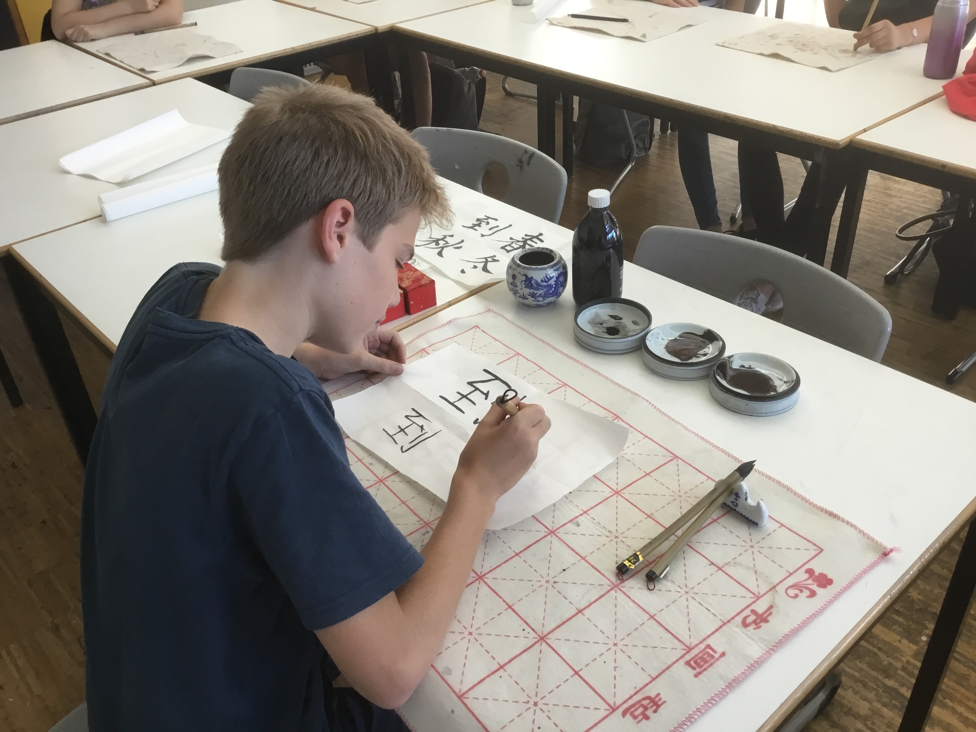 Emil Best benutzt einen Kalligraphie-Pinsel und Tusche, um chinesische Schriftzeichen auf Papier zu bringen.