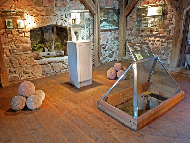 Bei der Verteidigung wurde die Torhalle durch ein Fallgitter geschützt. Im Vordergrund sieht man eine sogenannte Umlenkwalze mit der das Fallgitter gesenkt oder gehoben wurde. Ein Modell des Fallgitters verdeutlicht die Funktion der Vorrichtung.
Die bei den Renovierungsarbeiten gefundenen Sandsteinkugeln, wurden zur Verteidigung der Torhalle genutzt. Die Kugeln, wurden durch eine Öffnung dem sogenannten "Totschläger" auf den eingedrungenen Feind der sich in der Torhalle befand, hinabgeworfen. Die zerschellten Kugeln hatten eine Wirkung, wie Granatsplitter.  

 | Foto: Alfred Schramm