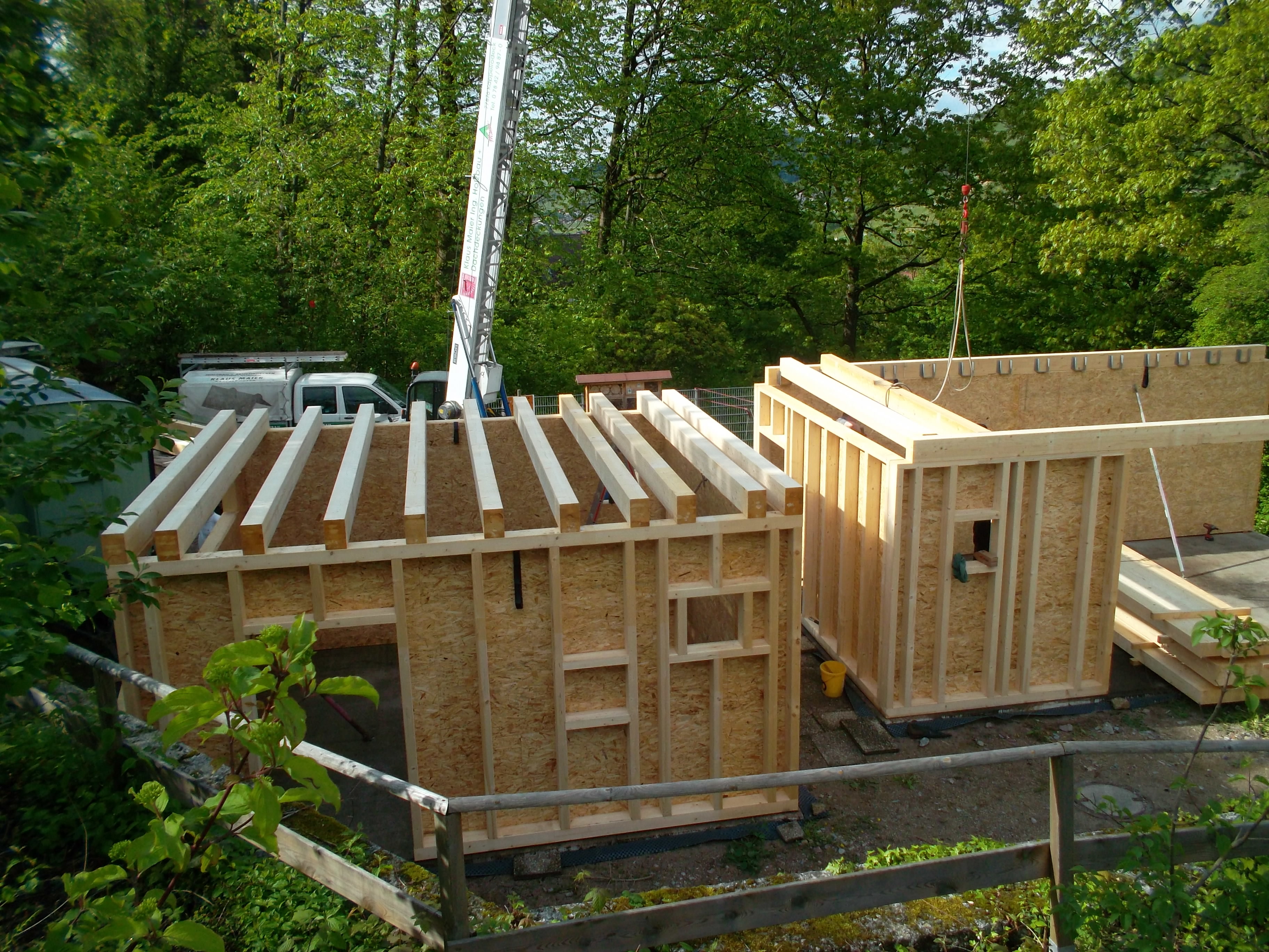 Seit vergangenem Freitag stehen die Holzbauwände beider Gebäude, demnächst wird die Außendämmung angebracht, das Gründach angelegt und Fenster und Türen eingebaut.