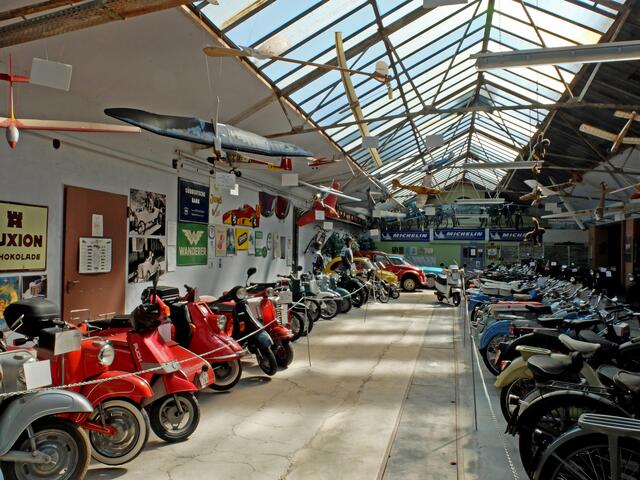 An der Hallendecke befinden sich Modellflugzeuge und unten diverse Motorroller, Motorräder und Mofas. | Foto: Alfred Schramm