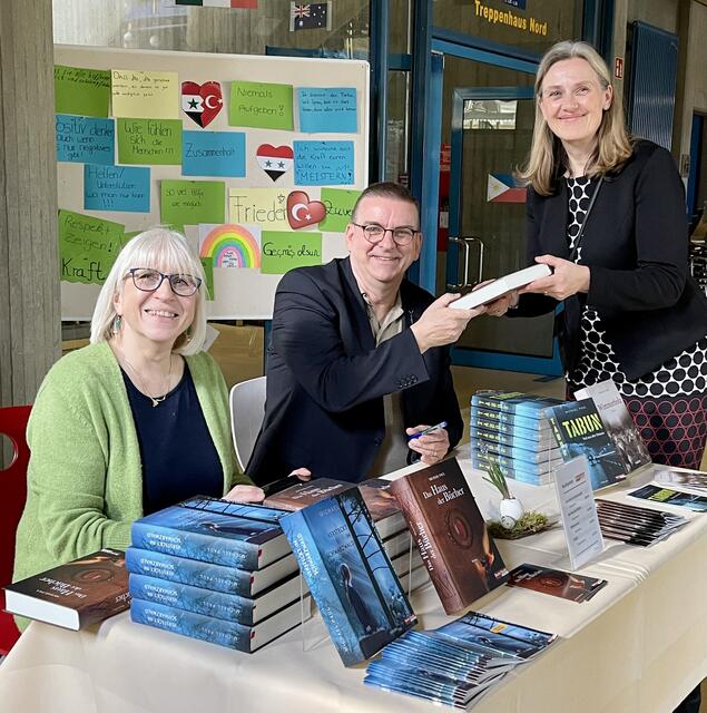 Autor beim anschließenden Bücherverkauf.
Links eine Vertreterin des Fördervereins Hilde Zipf, rechts die Schulleiterin Dr. Christina Seebeck