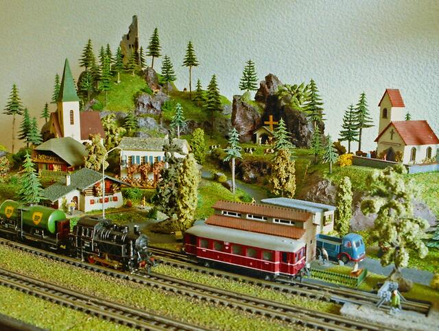 Zu sehen ist ein Landschaftsausschnitt von einer kleinen "Nostalgie-Anlage", mit einer TRIX EXPRESS Rangier-Tenderlok der Baureihe 80 (Kaufpreis 1956, 27,00 DM) und ein BP Kesseltankwagen (aus Blech) sowie der Anhänger eines VT 75 Triebwagens.  Im Hintergrund sieht man Modellhäuser der Firma FALLER aus Gütenbach. Diese Häuschen konnte man schon im Jahr 1952 erwerben. Im Vordergrund , das kleine Chalet  (7,50 DM), dahinter das Tessiner Haus (12,50 DM) und das Försterhaus  (7,50) DM. Weiterhin zu sehen, die Dorfkirche mit Geläut (12,50 DM), Burgruine (3,25) sowie zwei Kapellen.
Wenn man sich die damaligen Stundenlöhne, normaler Arbeitnehmer ansieht,   war das Modellbahnhobby nicht gerade billig.  | Foto: Alfred Schramm