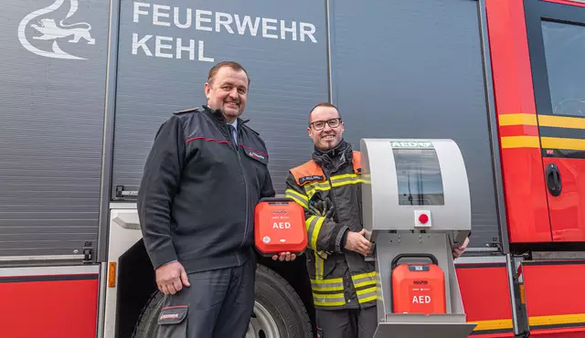 Feuerwehrkommandant Viktor Liehr (links) und Oberbrandmeister Sven Ruhland präsentieren einen der 25 automatisierten externen Defibrillatoren (kurz: AED), die in den nächsten Monaten rund um die Kernstadt sowie den Ortschaften aufgehängt werden.  | Foto: Lardjah Naba/Stadt Kehl