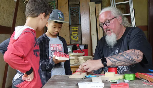 Jugendarbeiter Andreas Martzloff (rechts im Bild) zeigt den Kindern beim Ferienspaßprogramm, wie sie aus Nägeln, Faden und Holz kleine Kunstwerke schaffen können. | Foto: Norman Mummert/Stadt Kehl