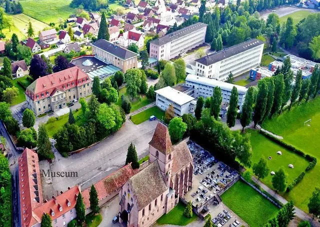 Im Vordergrund der Luftbildaufnahme sieht man die Kirche der Abtei Saint-Walburge und links das Gebäude, in dem sich das Museum mit seinen Ausstellungsräumen befindet.