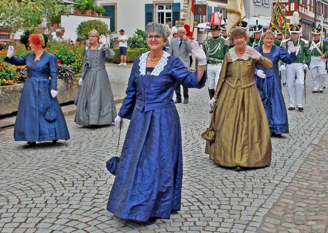 Die Damen der Alt-Gengenbacherinnen winken mit einem Lächeln den Gästen des Altstadtfestes fröhlich zu. Sie gehen in der Formation der Bürgergarde im Anschluss an den Fanfarenzug bei den Umzügen und mit ihren unterschiedlich gestalteten Kleidern entsteht ein schönes Bild inmitten der Uniformträger. | Foto: Alfred Schramm