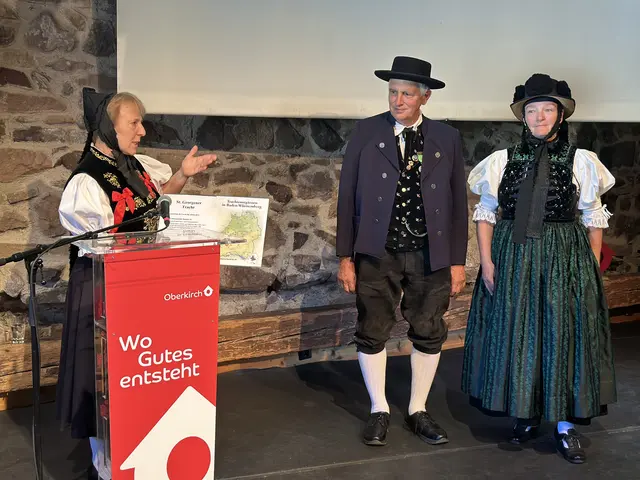 Kuratorin Anita Ellinger erläutert bei der Vernissage anhand einer Informationstafel die Herkunft und Besonderheiten der ausgestellten Trachten. Tafeln begleiten die Präsentation und geben Einblicke in die verschiedenen Trachtenregionen Baden-Württembergs.  | Foto: Denise Burkart/Stadt Oberkirch
