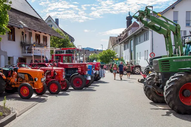 Bunte Reihe historischer Schlepper – darunter ein grüner Fendt Favorit mit Frontlader – parkt entlang der Biberacher Dorfstraße, Besucher schlendern beim Treffen zwischen den Fahrzeugen.