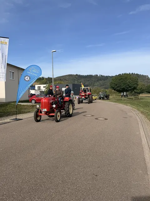Roter Traktor fährt auf einer Straße Richtung Gewerbegebiet.