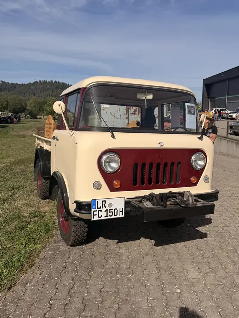 Cremefarbener Frontlenker-Lkw mit rotem Kühlergrill von vorn.