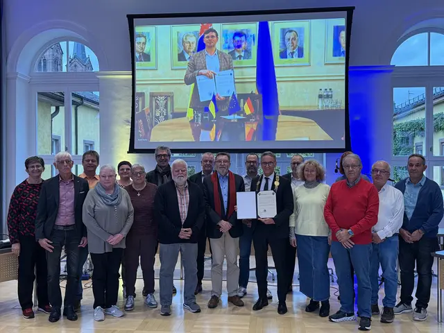 Lahrs Oberbürgermeister Markus Ibert (mit Amtskette), Kaluschs Bürgermeister Andrii Naida (auf der Leinwand) und Mitglieder des Lahrer Gemeinderats präsentieren die unterzeichneten Partnerschaftsurkunden. | Foto: Stadt Lahr